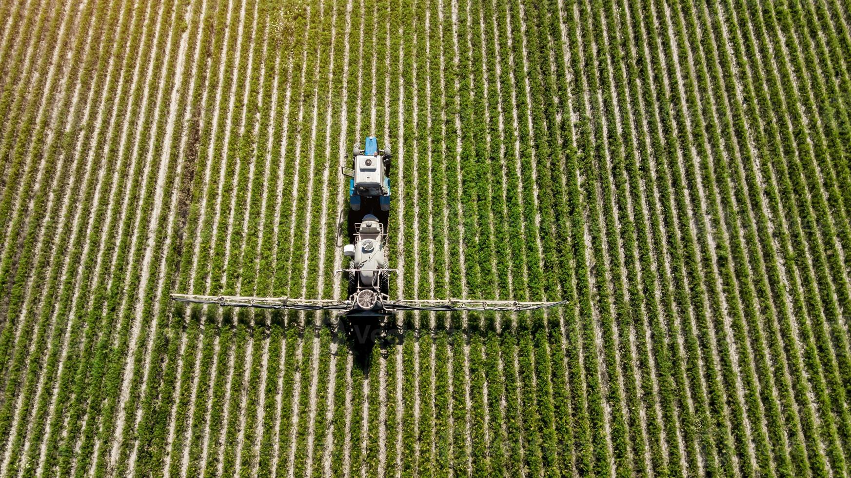 Luftaufnahme der landwirtschaftlichen Spritze, die an einem sonnigen Tag auf der grünen Wiese arbeitet foto