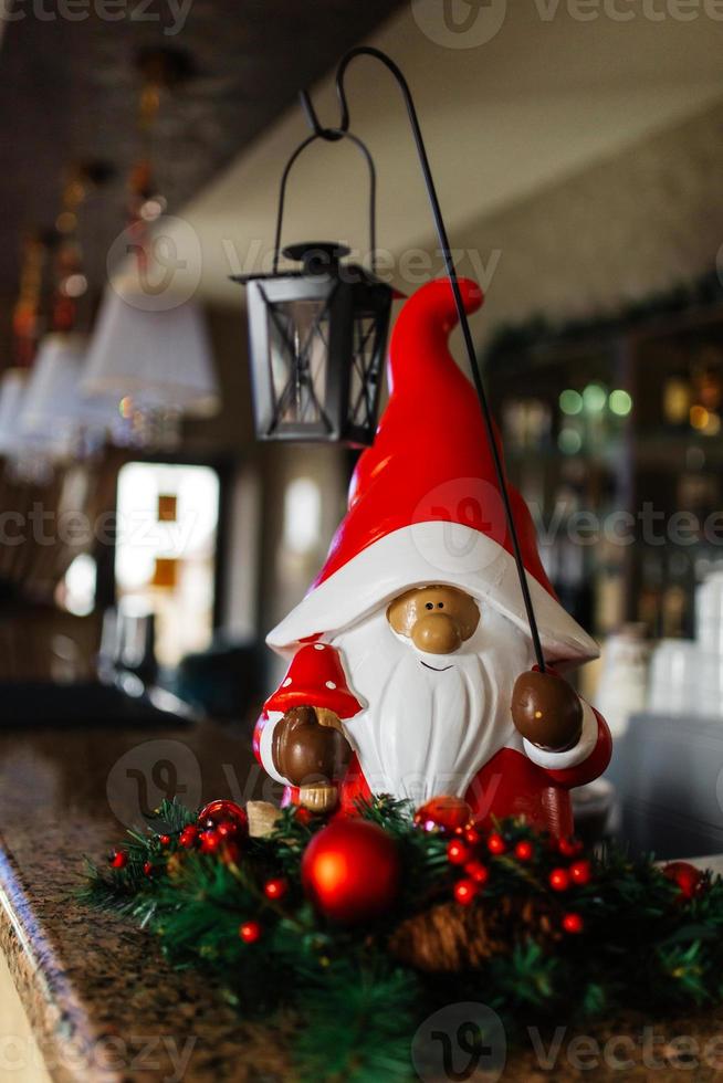 Märchenzwerg mit einer Weihnachtslaterne unter dem Weihnachtsbaum. Weihnachtsdekoration im Café. Weihnachtsstimmung. foto