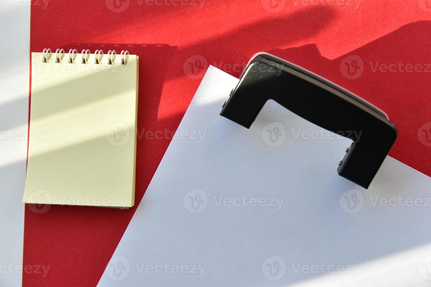 Bleistifte Locher und Notizblock auf rotem Grund foto