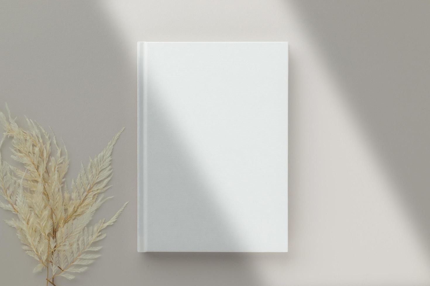 Weißes Buch Blanko-Cover-Mockup auf beigem Hintergrund mit trockener Blume, flache Lage, Mockup foto