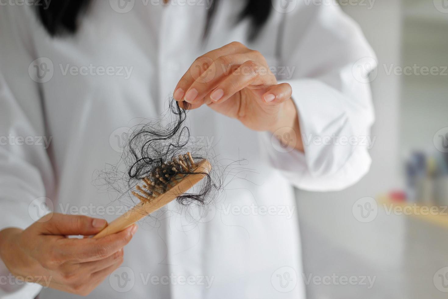 Frau verliert Haare auf Haarbürste in der Hand, weicher Fokus foto