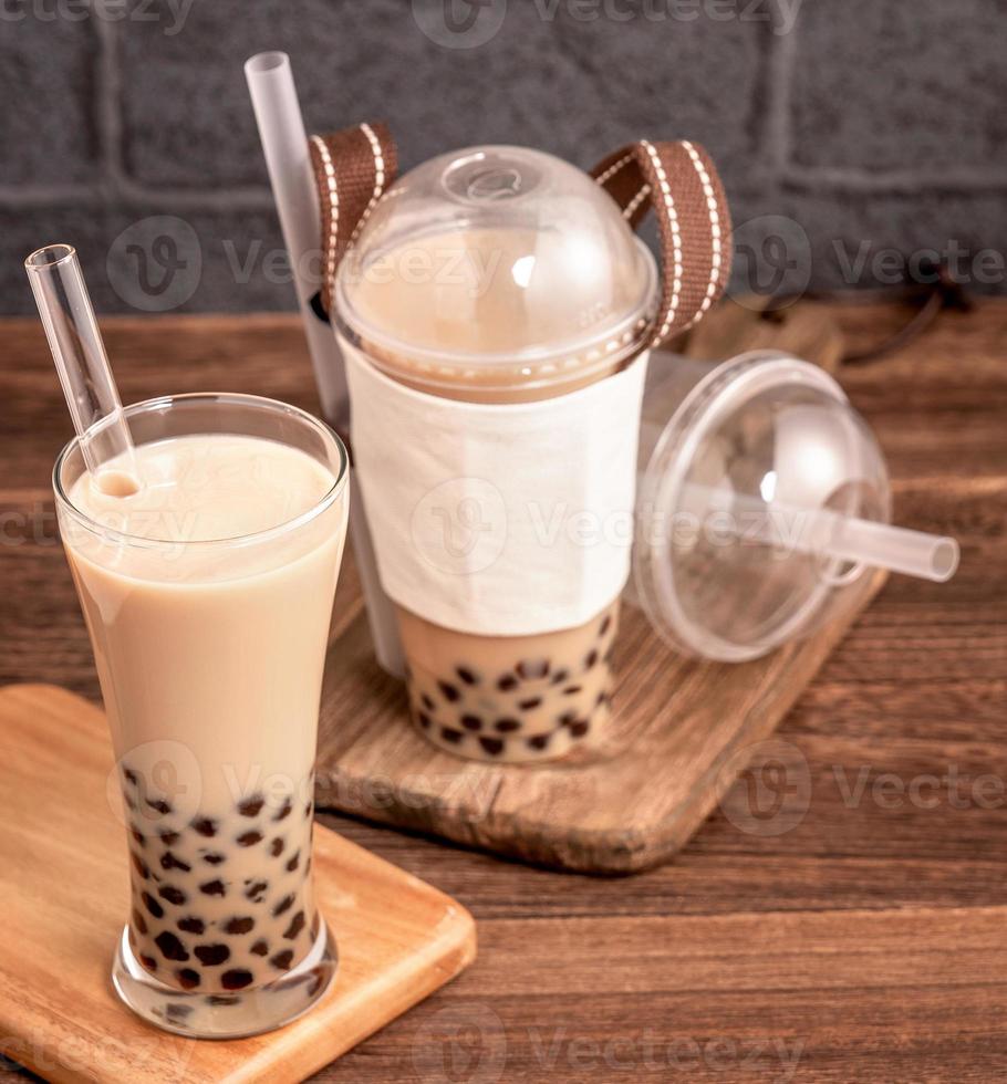 zum Mitnehmen mit Einwegartikel-Konzept beliebter taiwaner Getränk Bubble Milk Tea mit Plastikbecher und Strohhalm auf Holztischhintergrund, Nahaufnahme, Kopierraum foto
