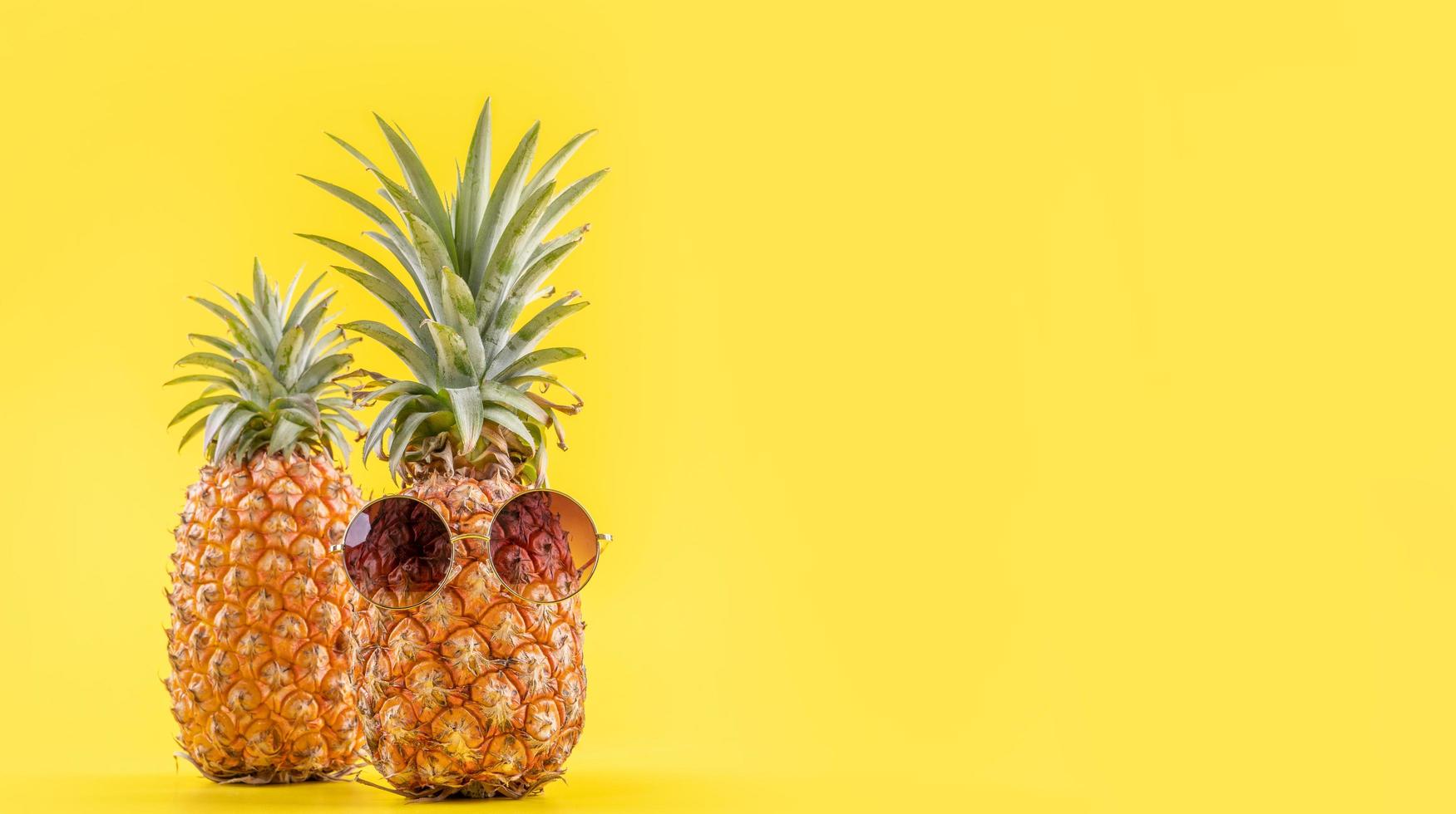 kreative ananas, die mit sonnenbrille und schale isoliert auf gelbem hintergrund nach oben schaut, sommerurlaub strandidee designmuster, kopierraum nah oben foto