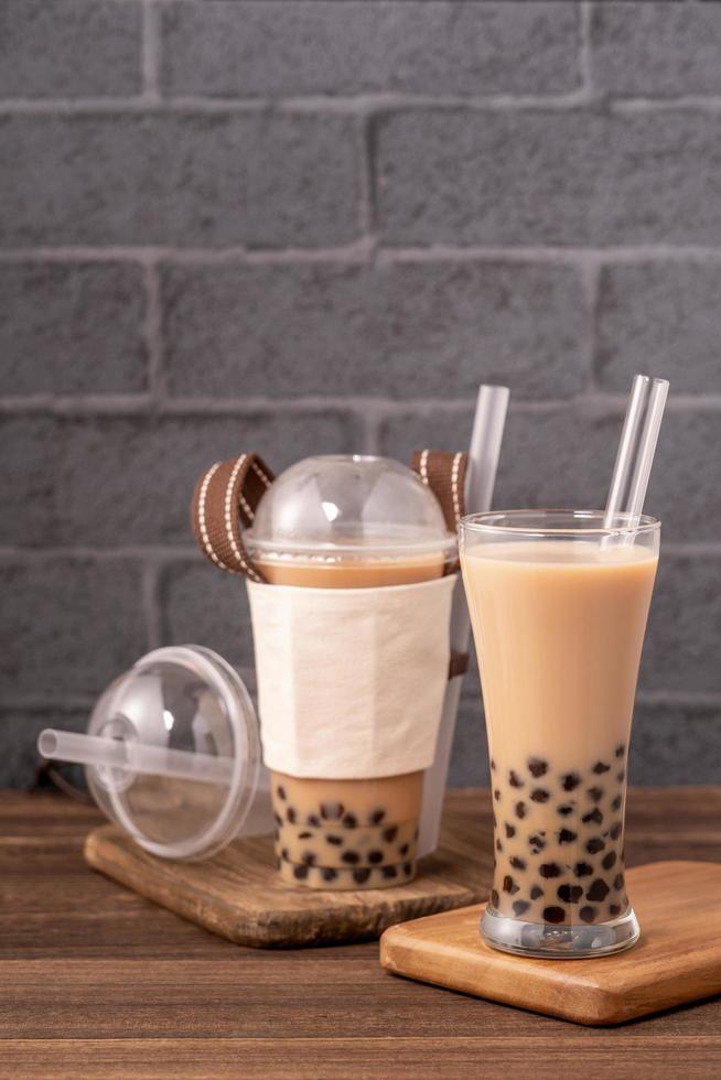 zum Mitnehmen mit Einwegartikel-Konzept beliebter taiwaner Getränk Bubble Milk Tea mit Plastikbecher und Strohhalm auf Holztischhintergrund, Nahaufnahme, Kopierraum foto