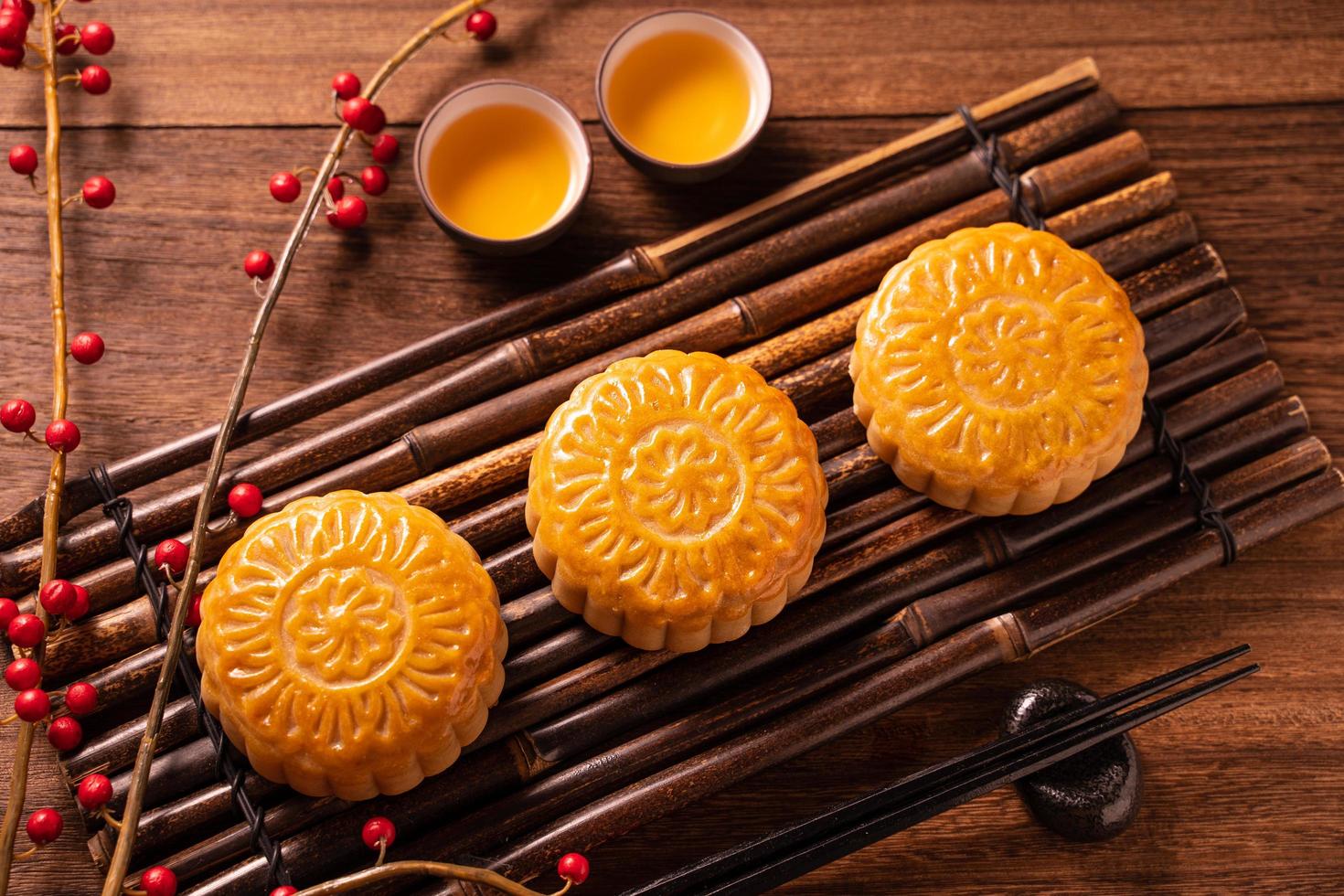 Mondkuchen Mondkuchen-Tischdekoration - rundes chinesisches traditionelles Gebäck mit Teetassen auf Holzhintergrund, Mitte-Herbst-Festival-Konzept, Nahaufnahme. foto