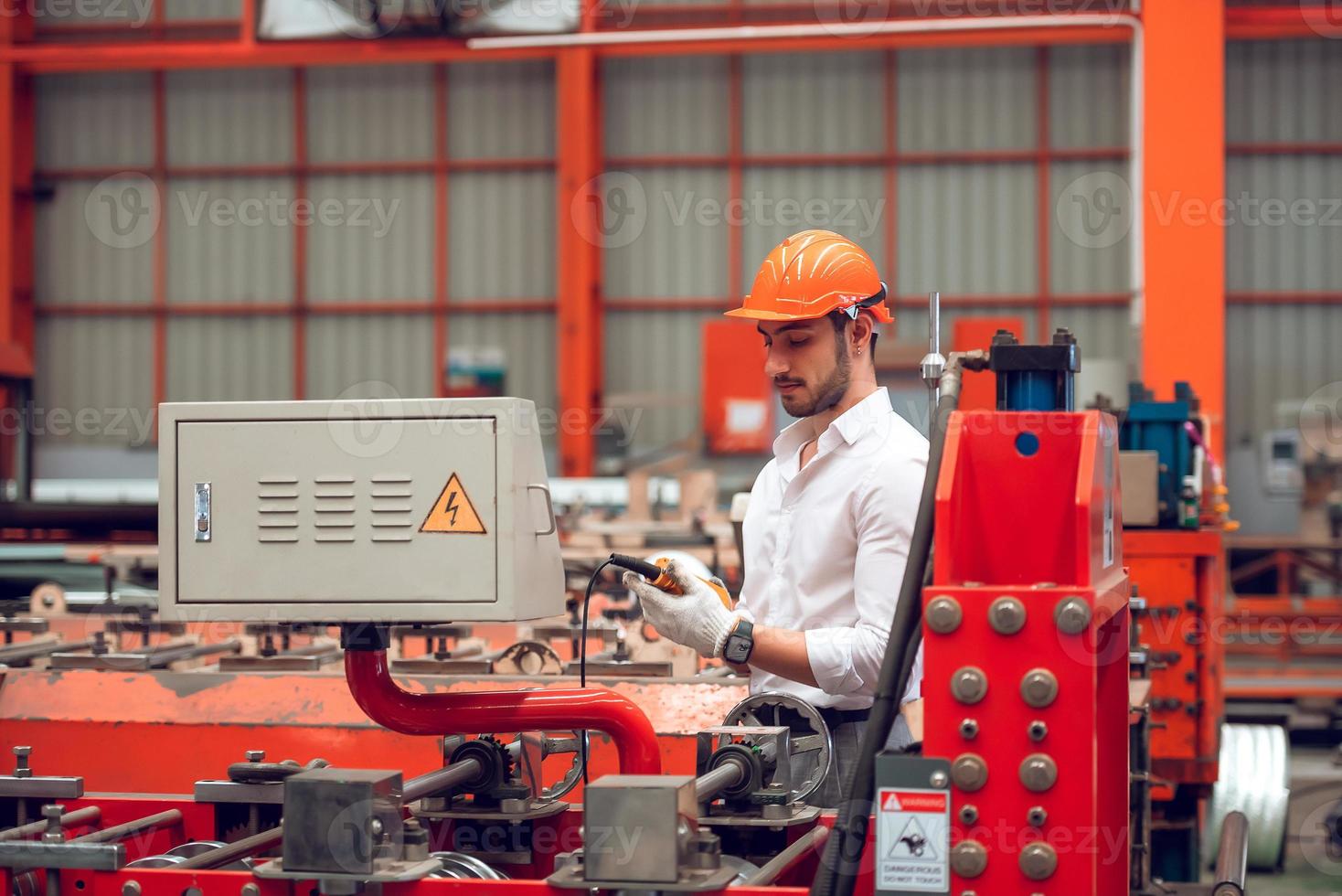 fabrikarbeiter, der den prozess der elektrischen maschine auf der industriearbeitsstelle überprüft und aus sicherheitsgründen einen harten hut trägt foto