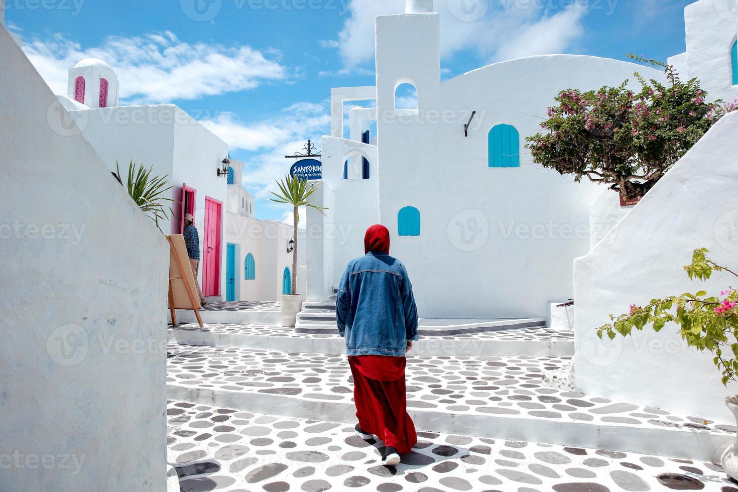 muslimische frau, die vor dem traditionellen griechischen hausstil von santorini bei agrowisata bhumi merapi geht foto