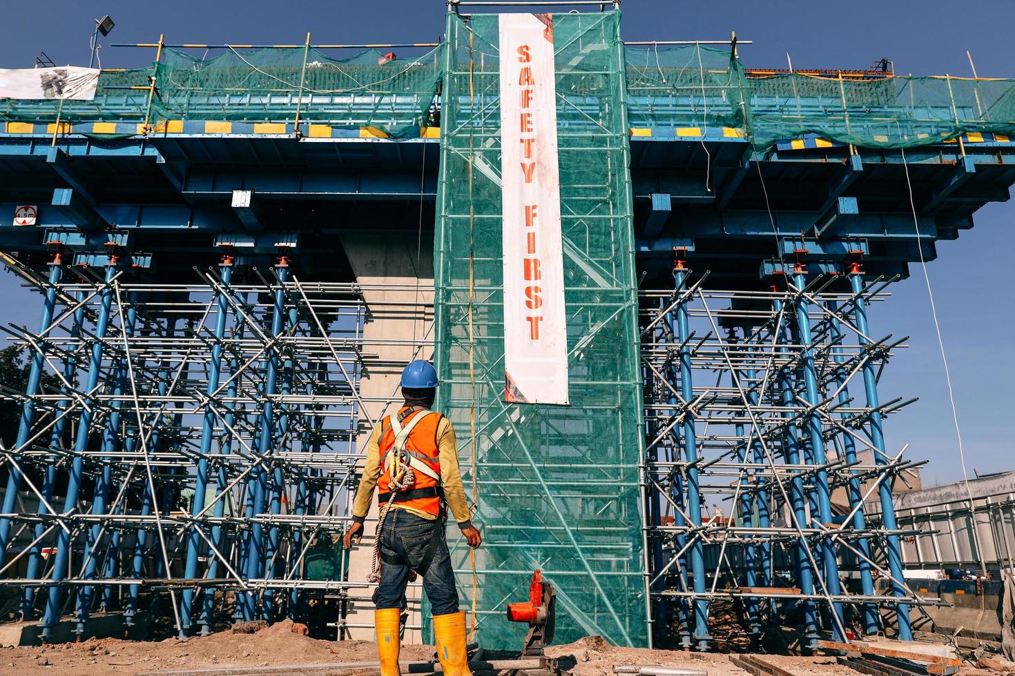 ingenieur in sicherheitsschutzausrüstung, der vor dem im bau befindlichen gebäude mit sicherheitsbanner steht. Bandung, Indonesien – 17. März 2022 foto