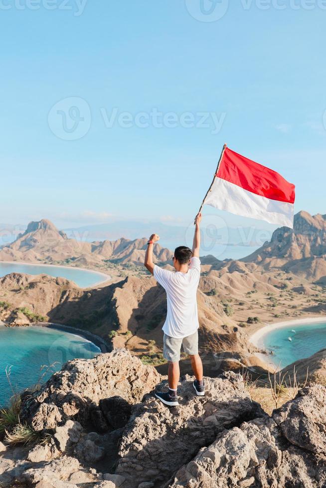 ein mann, der die indonesische flagge auf den hügeln der insel padar labuan bajo schwenkt foto