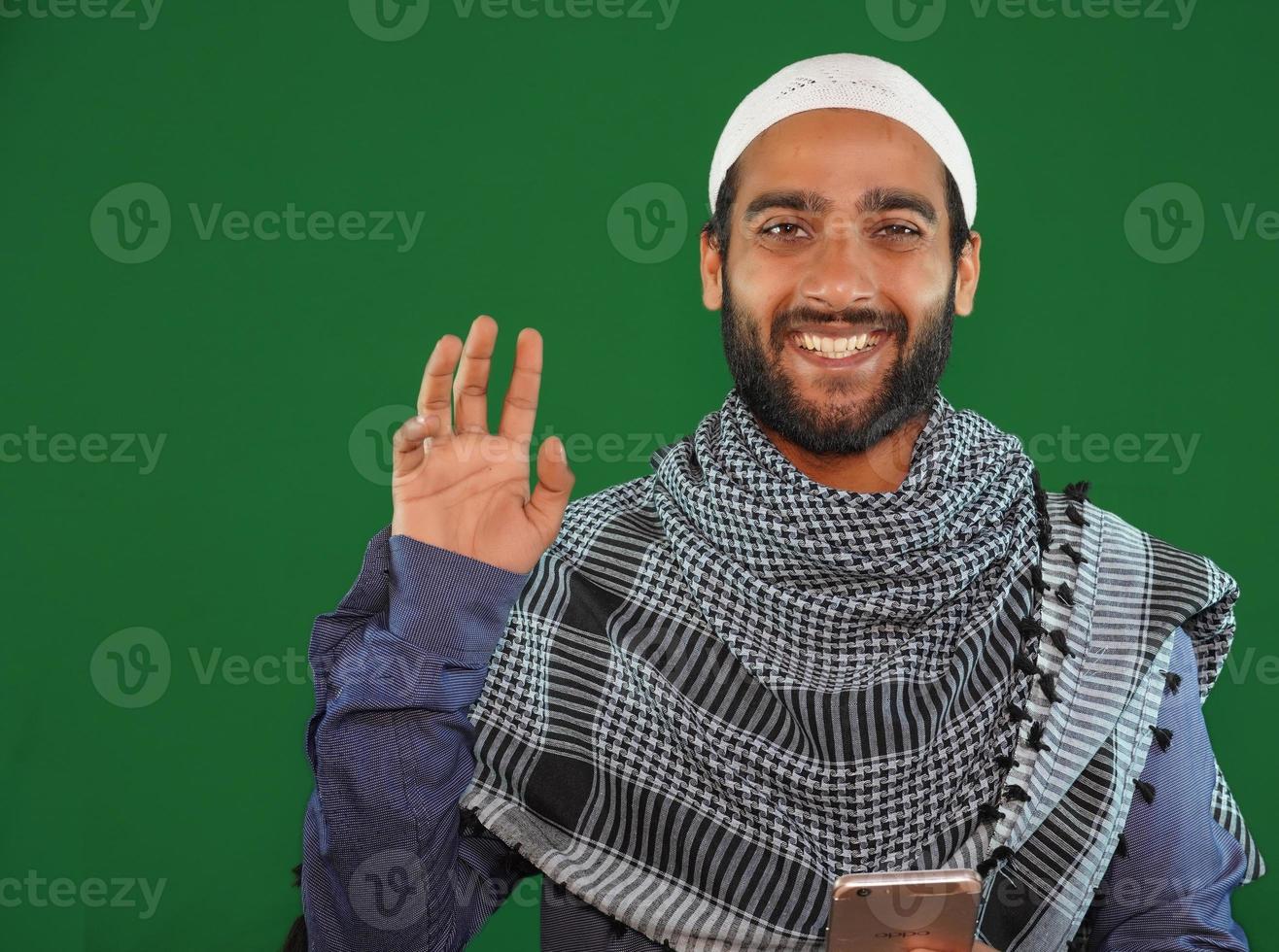 muslimischer junge sagt hallo auf grünem bildschirmhintergrund. foto