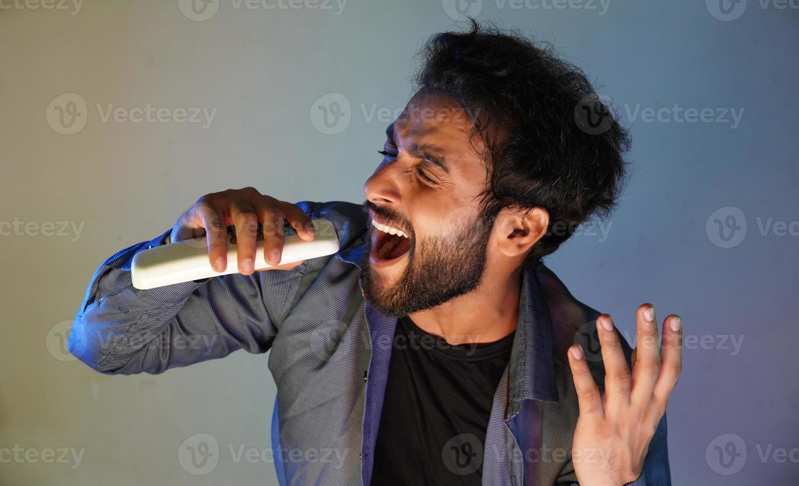 Der Mann versucht, mit seinem Mikrofon eine hohe Note zu singen foto