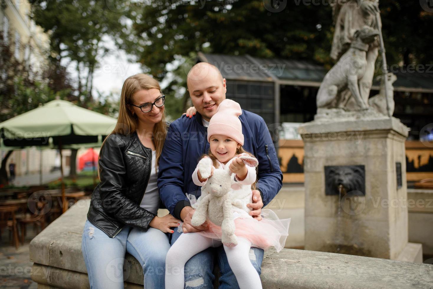 eltern und ihre tochter sitzen auf den stufen einer alten kirche. foto