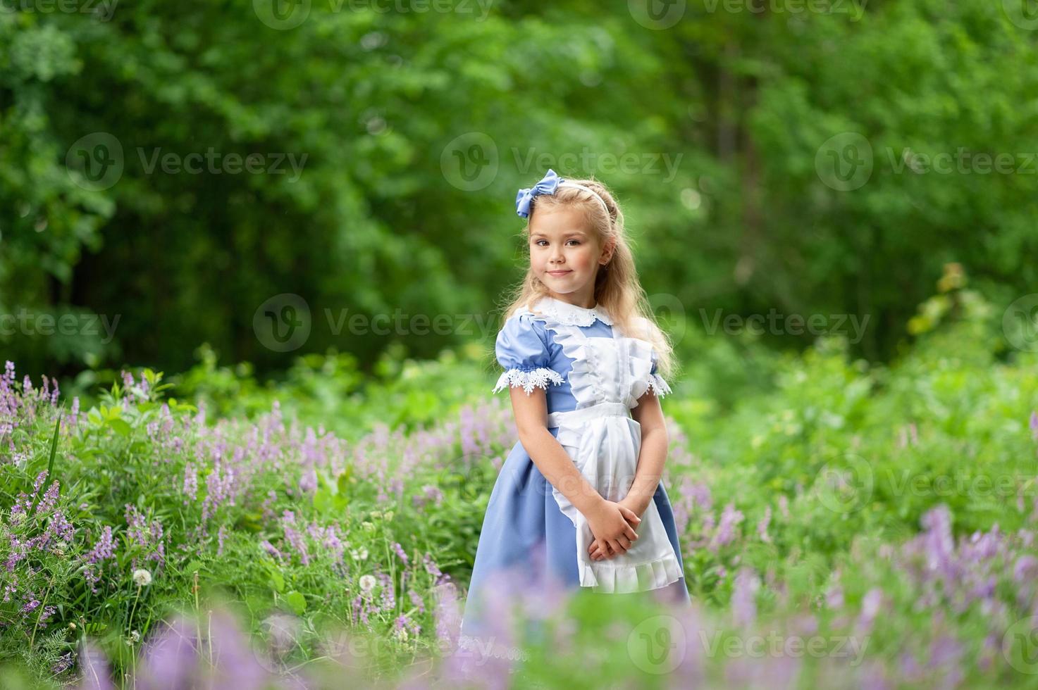 Porträt eines kleinen süßen Mädchens, das als Alice verkleidet ist. stilisiertes Fotoshooting in der Natur. foto