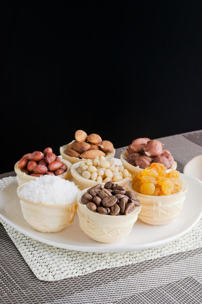 Waffelkörbchen mit Kaffeebohnen, Kokosnuss, Rosinen, Mandeln, Erdnüssen, Haselnüssen und Pinienkernen foto