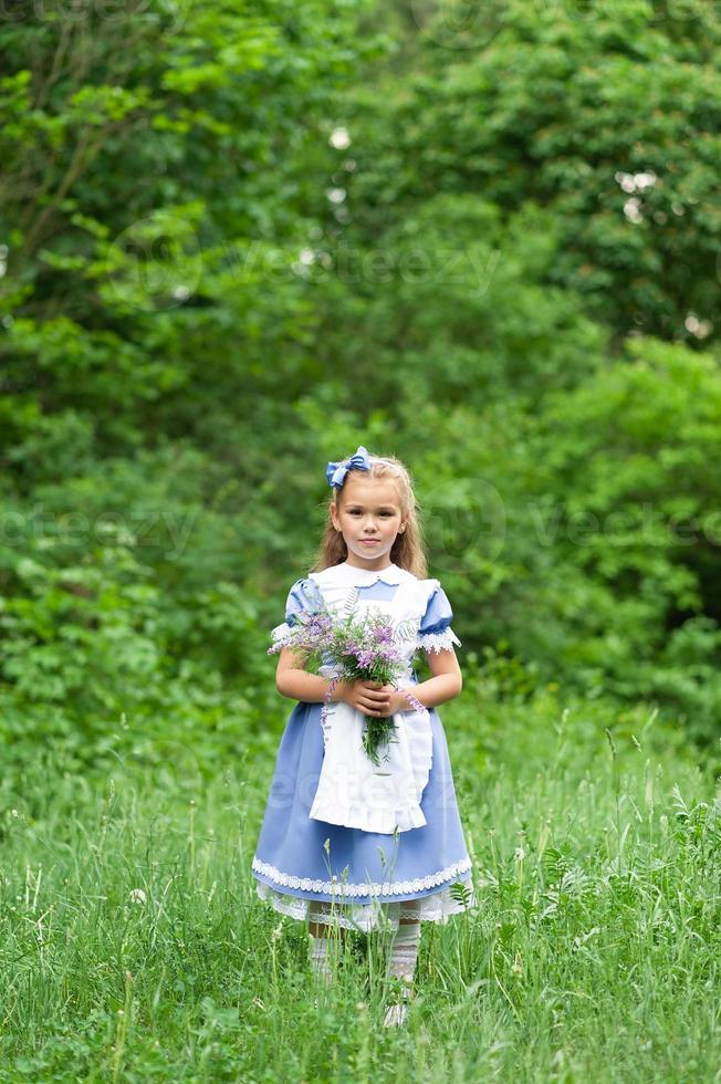 Porträt eines kleinen süßen Mädchens, das als Alice verkleidet ist. stilisiertes Fotoshooting in der Natur. foto