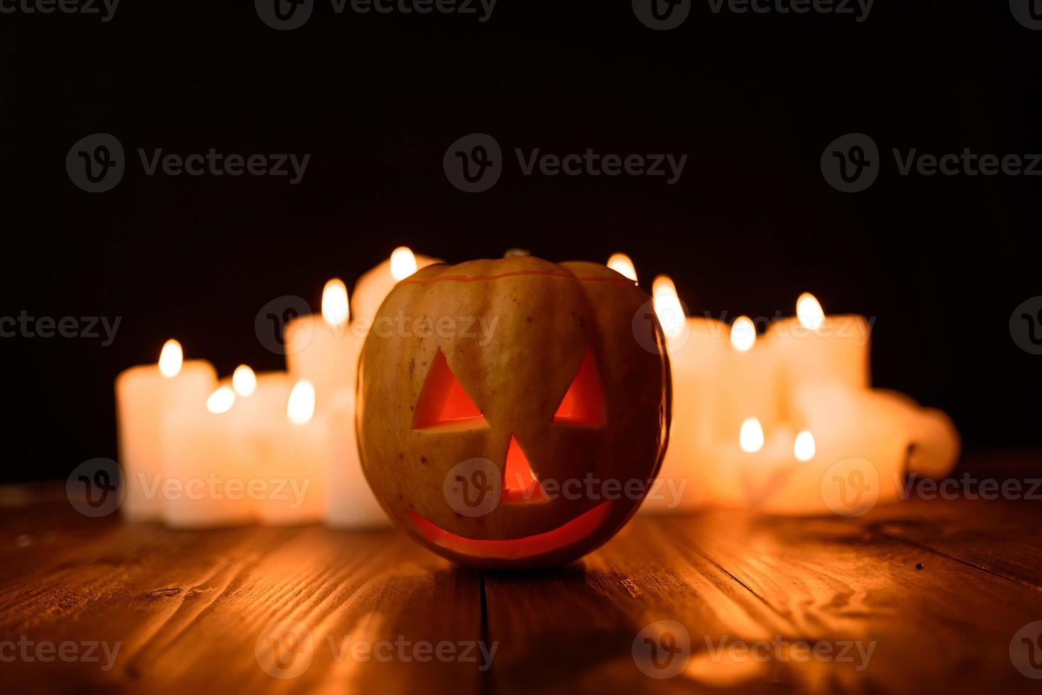Halloween-Kürbis auf dem Hintergrund von Kerzen und schwarzem Hintergrund. foto
