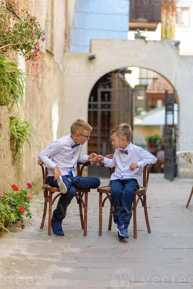 zwei kleine Jungen, Brüder sind in einem Anzug gekleidet. Kinder stehen im Park und umarmen sich. foto