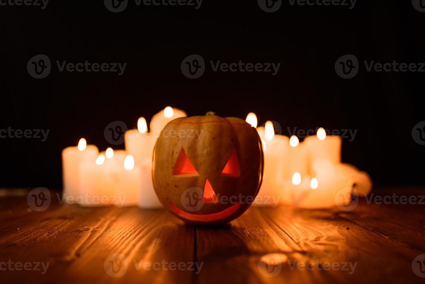 Halloween-Kürbis auf dem Hintergrund von Kerzen und schwarzem Hintergrund. foto