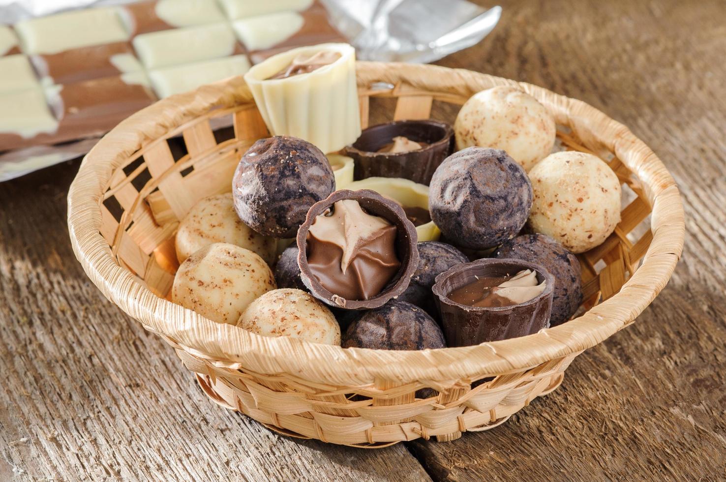 Pralinen und Schokolade in einem Korb auf einem Holztisch foto