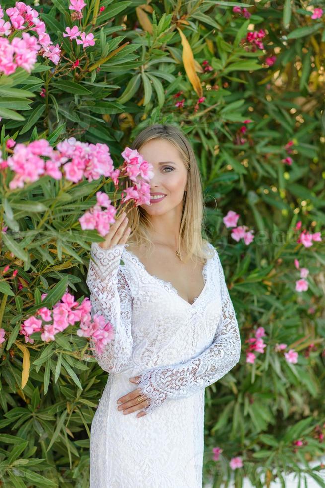 Porträt einer schönen Braut in einem weißen Kleid in einem Blumenbusch. foto