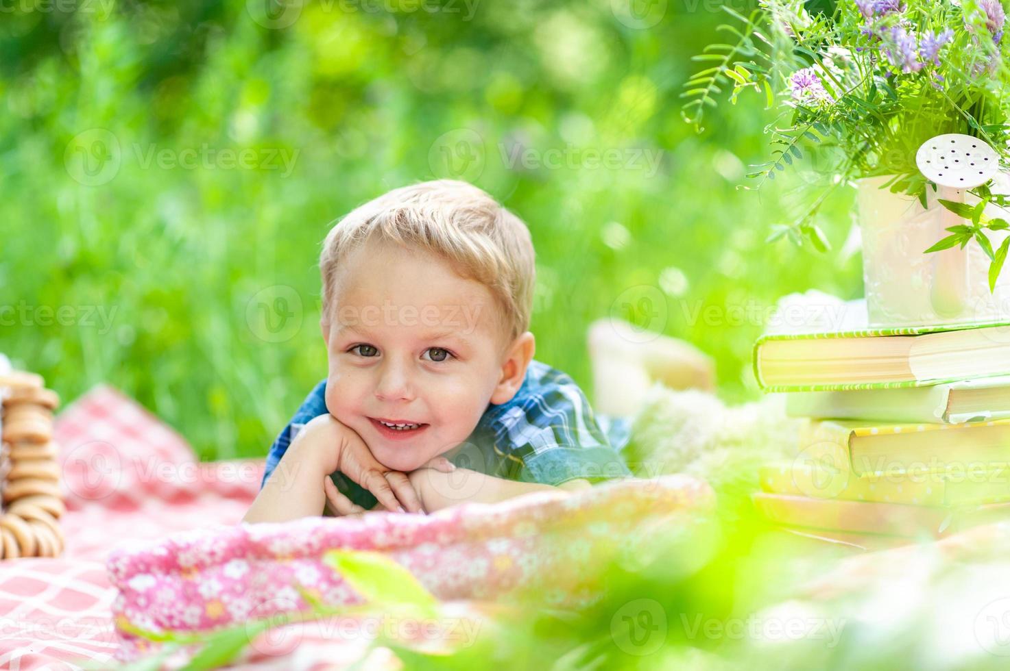 Der kleine süße Junge liegt auf einem Plaid auf dem Bauch und ruht auf den Ellbogen seiner Hände. Der Junge schaut in den Rahmen. Platz für ein Logo. foto