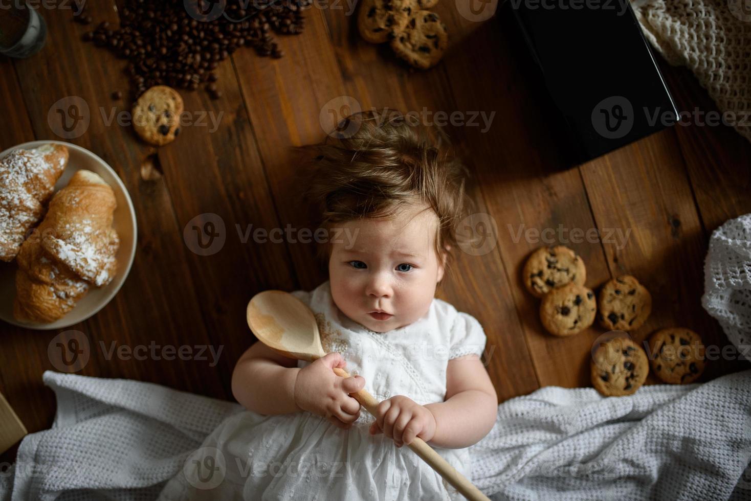 Kleine Köchin mit einem Holzlöffel bereitet das Mittagessen zu. foto