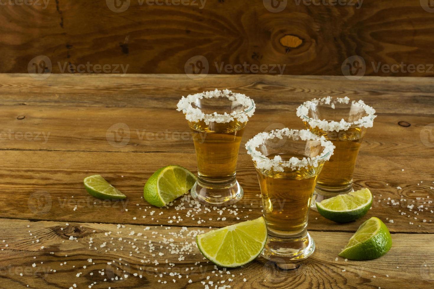 drei schüsse gold tequila auf dem hölzernen hintergrund foto