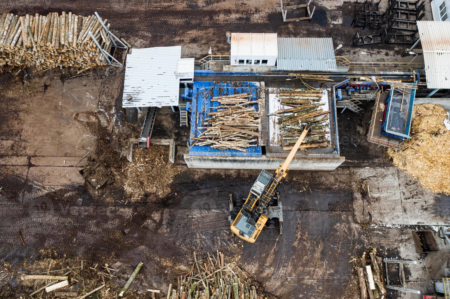 Ein Lader lädt Holzstämme in einer Holzverarbeitungsfabrik von oben von einer Drohne foto