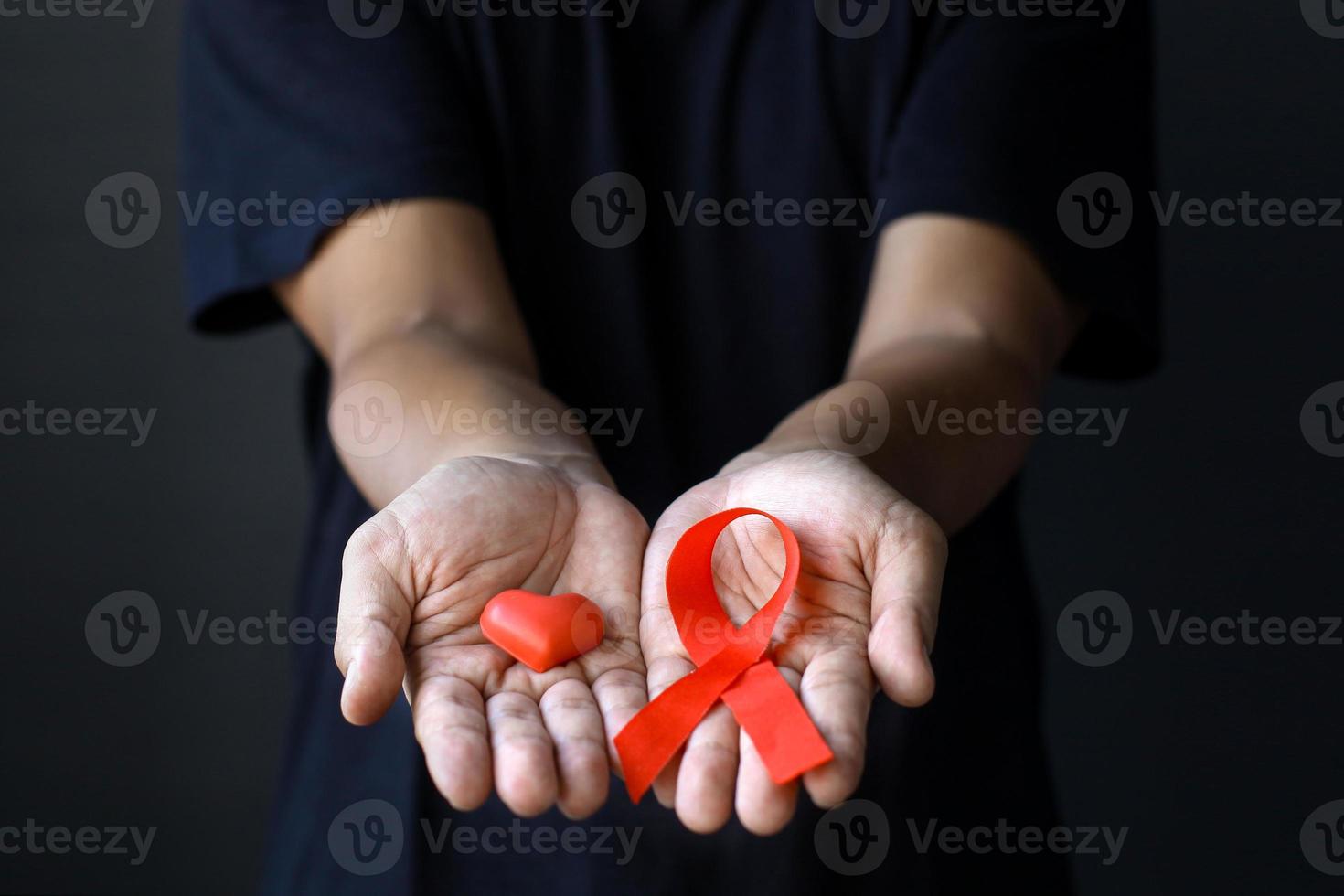 Welt-Aids-Tag und Welt-Diabetes-Tag mit männlichen Händen, die ein rotes Aids-Bewusstseinsband halten. Gesundheits- und Medizinkonzept. foto
