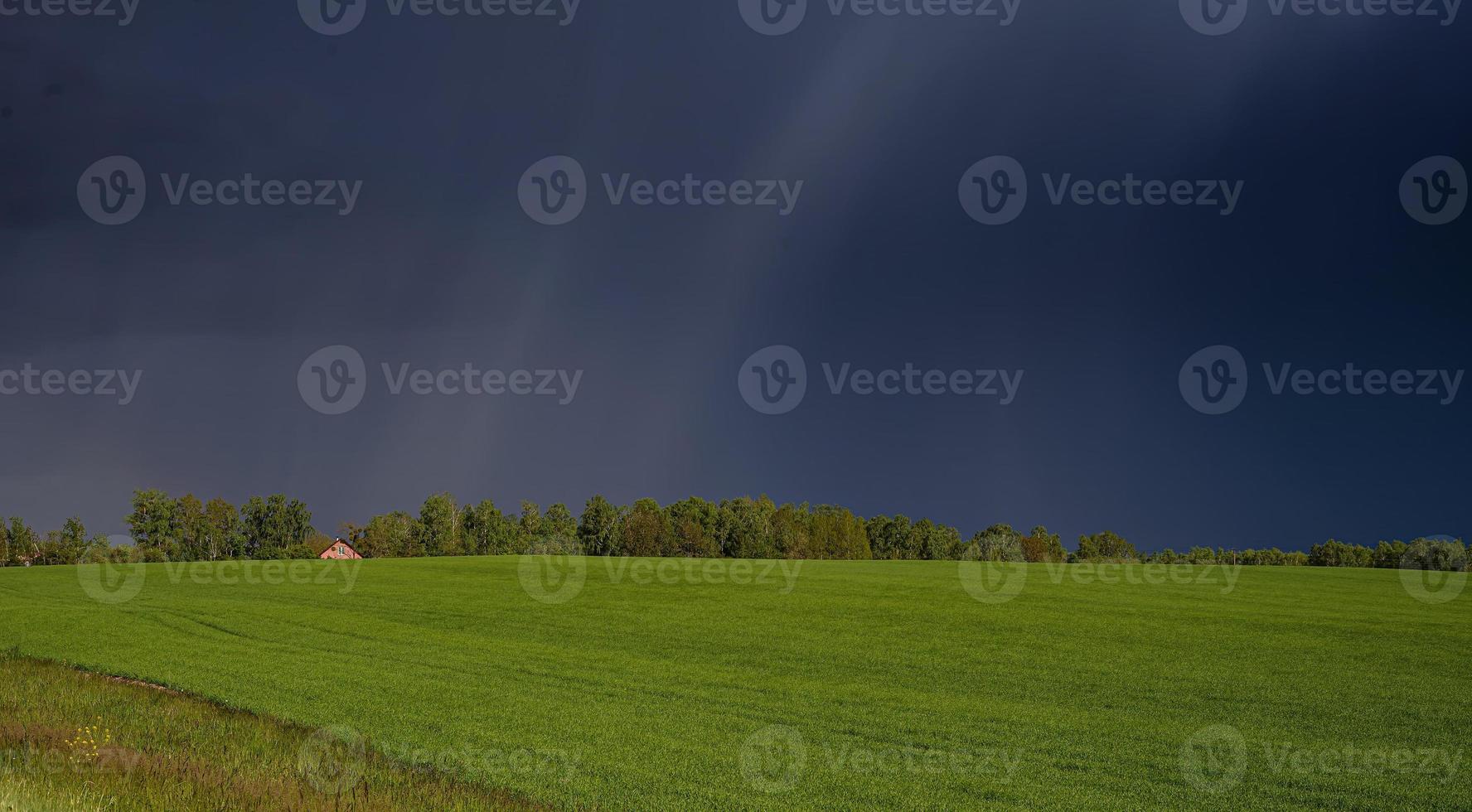 Ein einsames Haus inmitten einer grünen Wiese und einem stürmischen Himmel foto