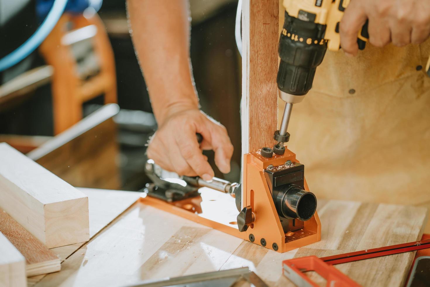 tischler verwenden schnurlose bohrer und taschenlochlehre oder dübellehre, fahren die schraube auf holzplatte, diy maker und holzbearbeitungskonzept. selektiver Fokus foto