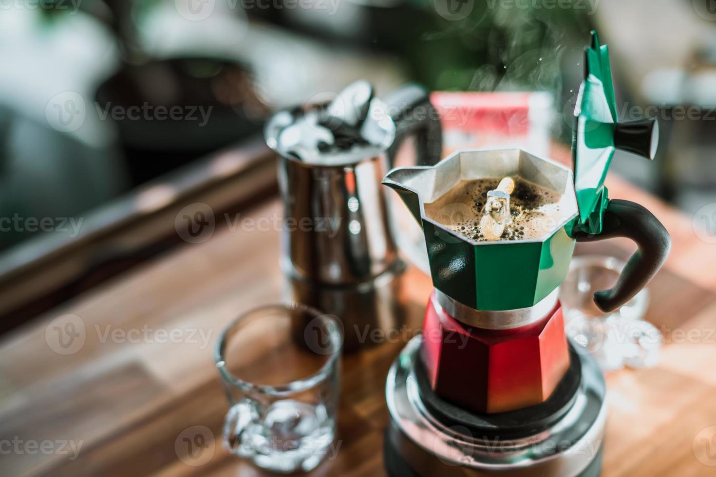 heißer kaffee in der moka-kanne auf dem elektroherd, vintage-kaffeemaschine auf dem holztisch zu hause, selektiver fokus. foto