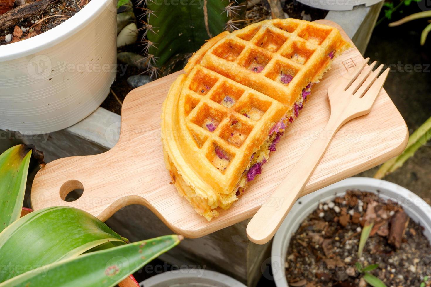 köstliche Waffeln lila Süßkartoffelgeschmack auf der Holzplatte im Garten. foto