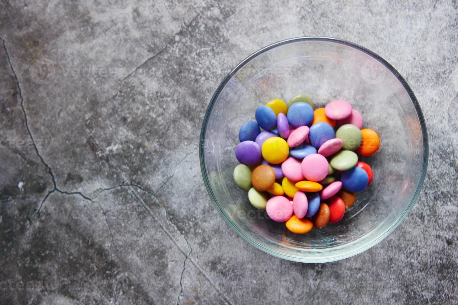 Kinderjunge, der mehrfarbige süße Bonbons in einer Schüssel pflücken, Nahaufnahme foto