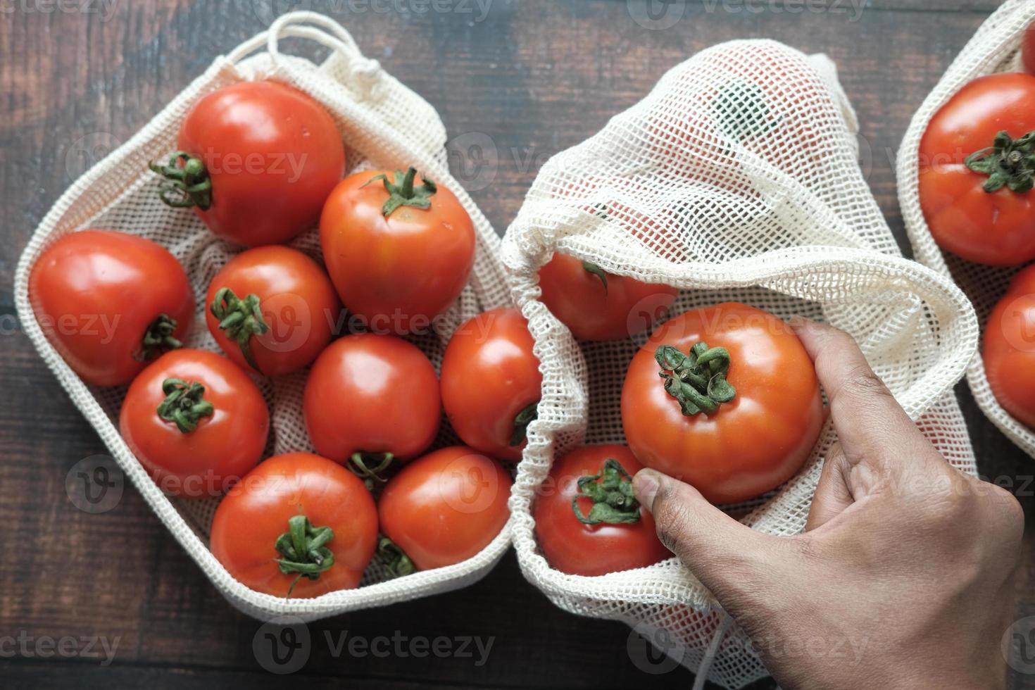 Hand einer Person, die Tomaten aus einer Einkaufstasche pflückt foto