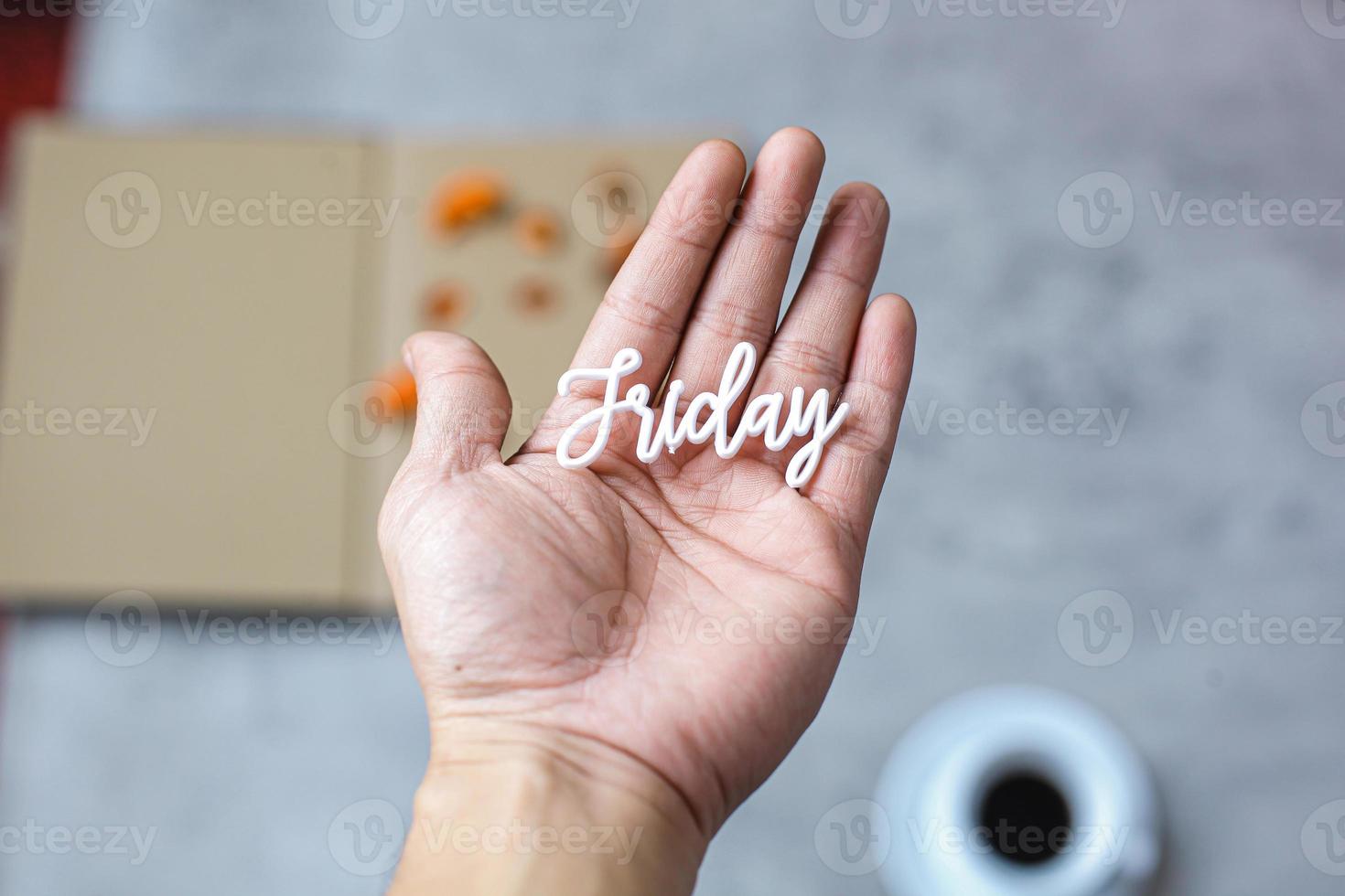 Hand, die Freitag-Wort auf verschwommenem Hintergrund hält foto