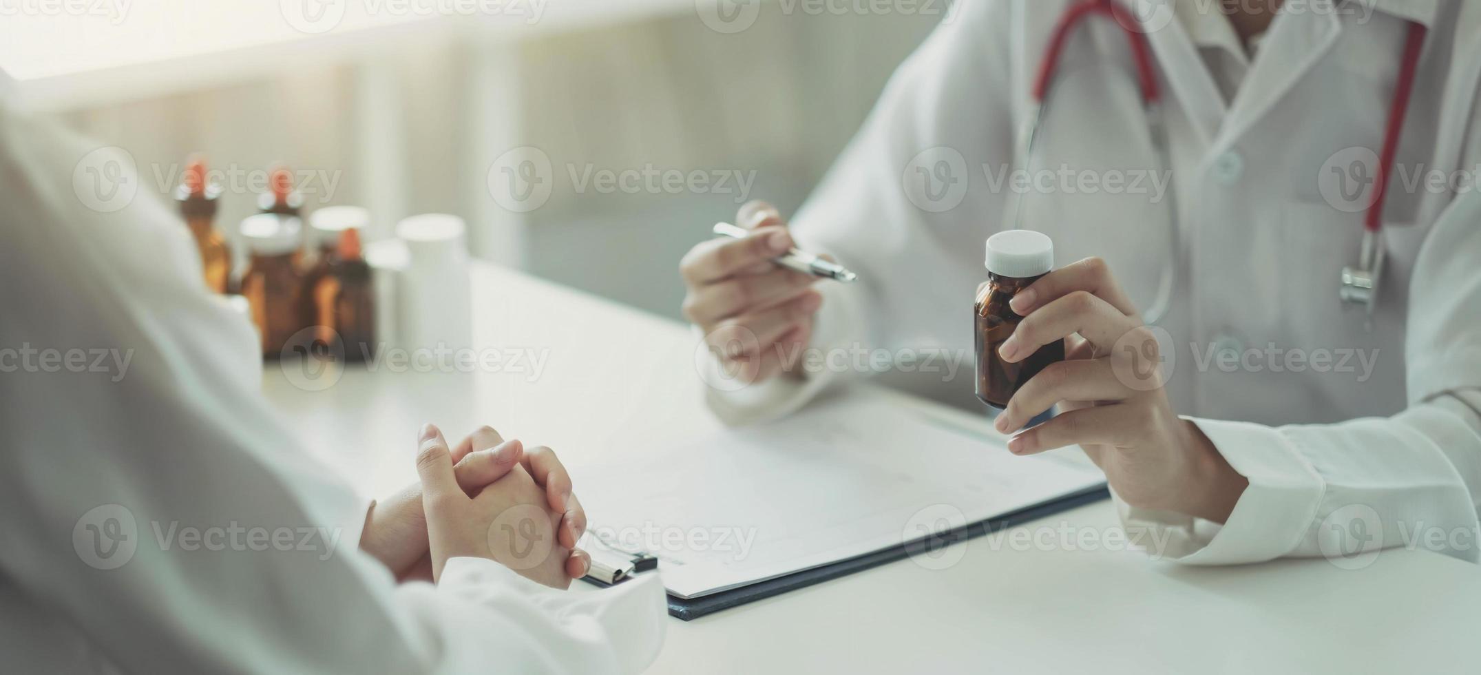 Selbstbewusster Mann und Frau, die eine Tablettenflasche halten, während sie mit dem Patienten sprechen und die Medizin im Büro überprüfen. foto