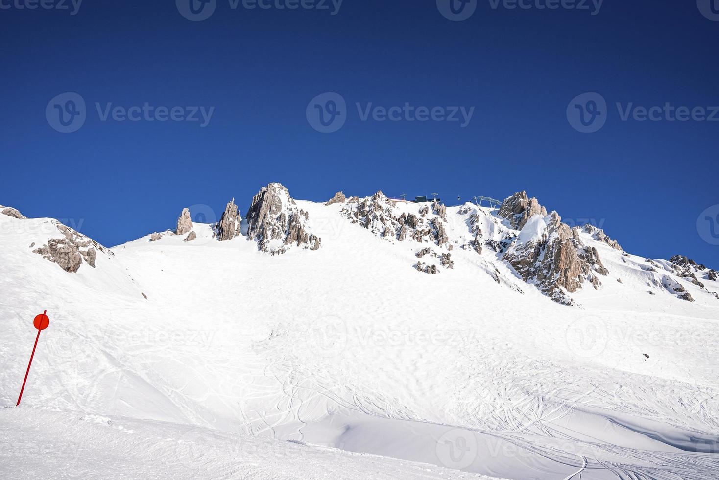 Skipisten auf schneebedeckten Bergen gegen den klaren Himmel in den Alpen foto