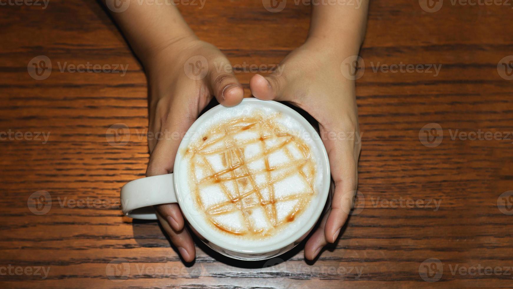 Hand halten heißen Kaffee im Heißgetränkkonzept auf Holztisch foto