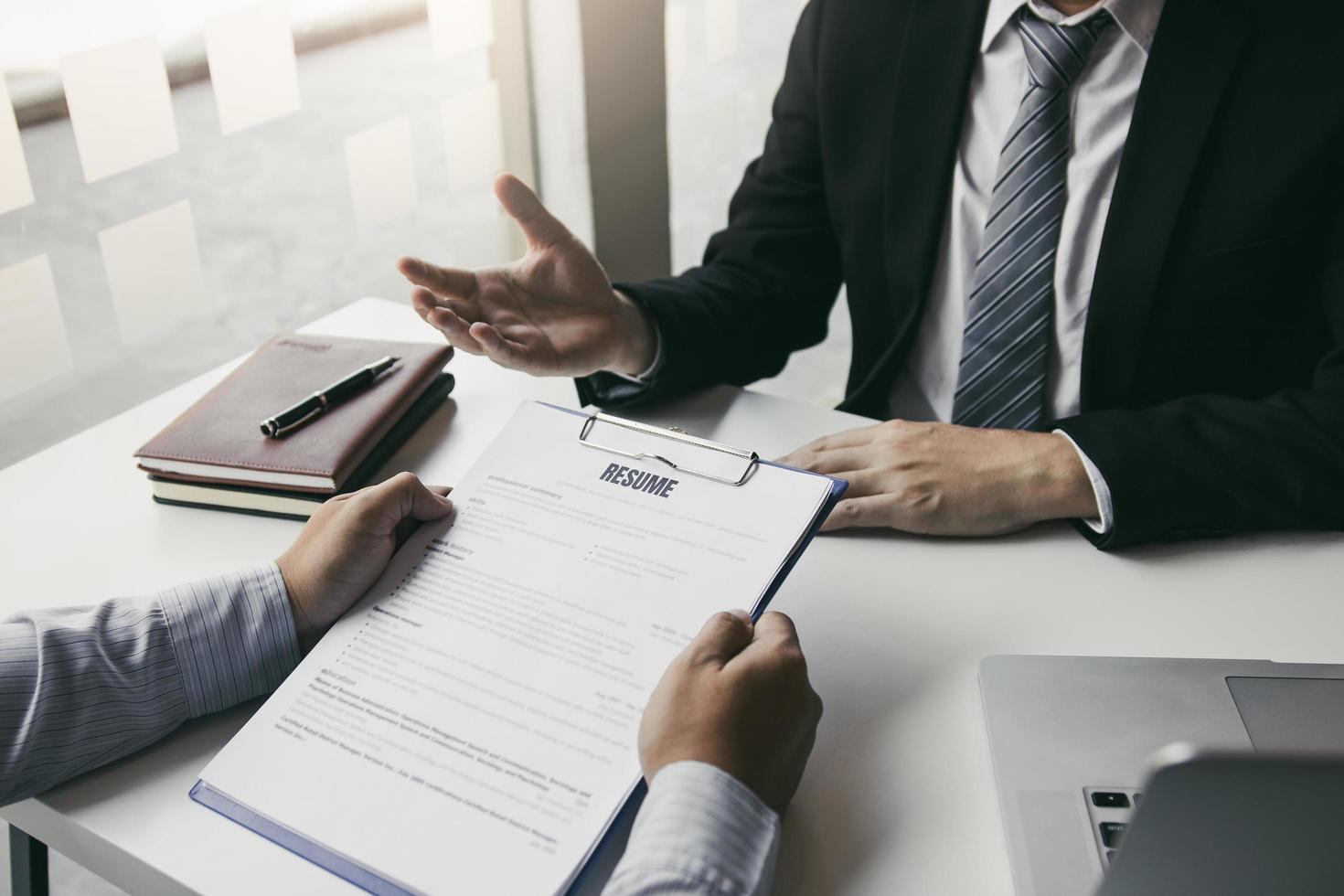 intelligenter geschäftsmann, professioneller mann im anzug, der bei einem treffen mit einem interviewmitarbeiter über die arbeit in einem modernen büro gestikuliert und spricht. foto