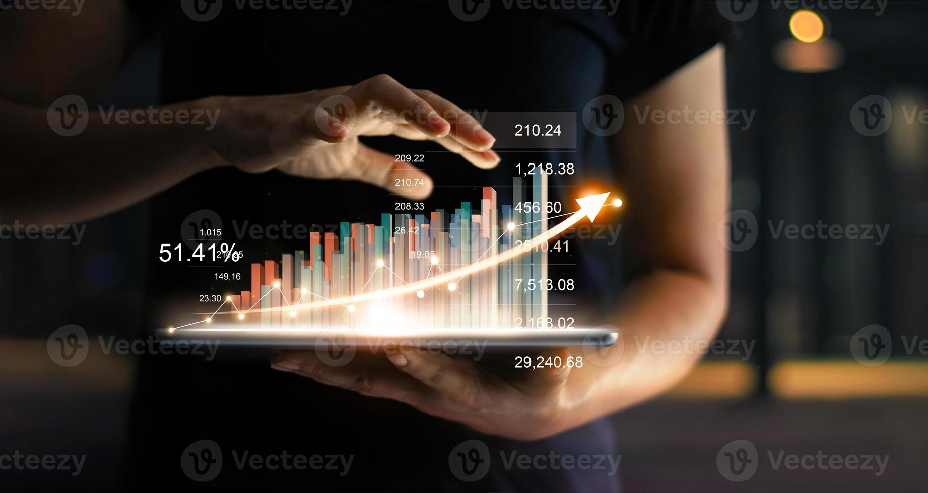 Geschäftsmann hält Tablet und zeigt ein wachsendes virtuelles Hologramm von Statistiken, Grafiken und Diagrammen mit Pfeil nach oben auf dunklem Hintergrund. Aktienmarkt. geschäftswachstum, planung und strategiekonzept. foto