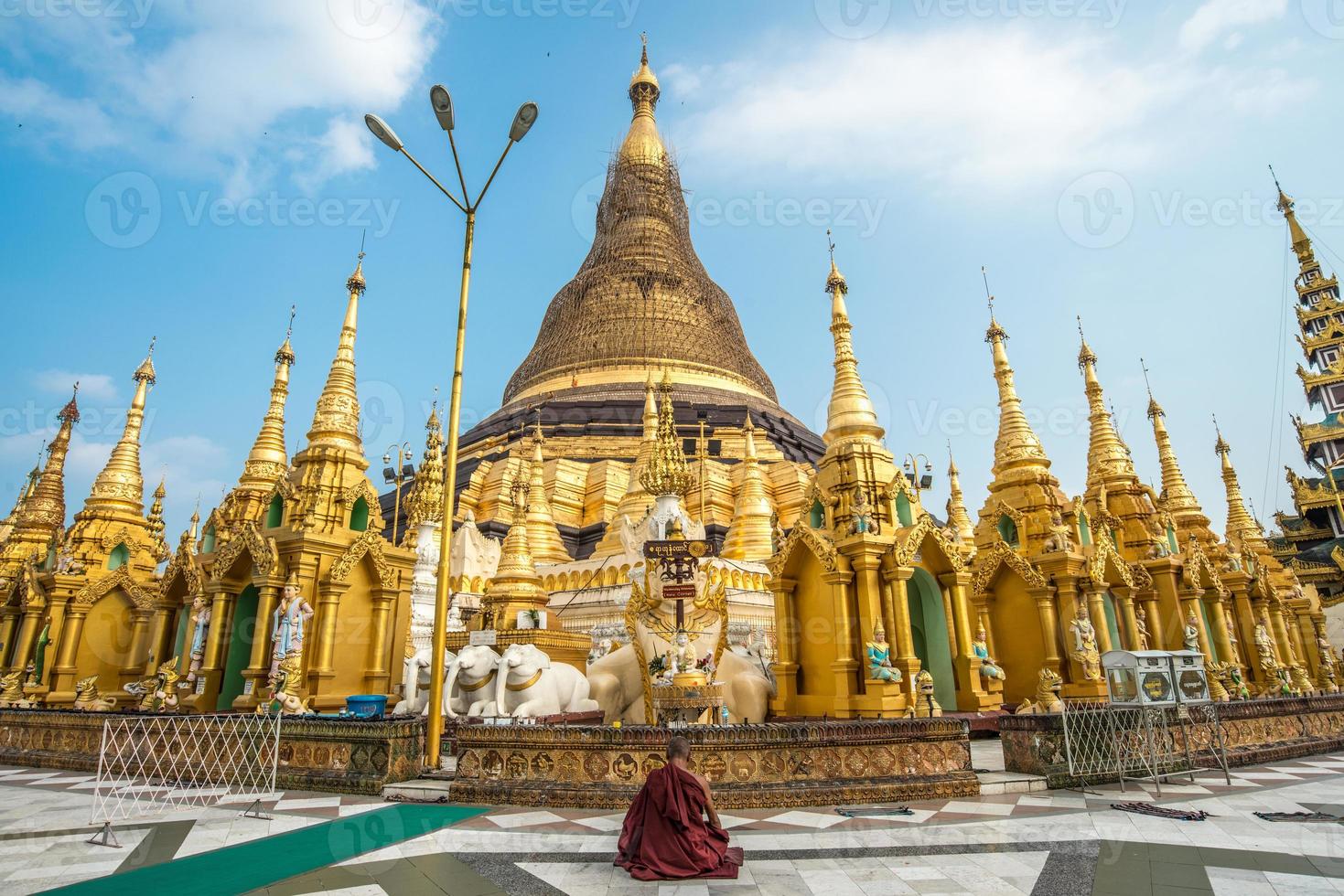 buddhistischer mönch sitzt und meditiert vor der shwedagon-pagode, einem ikonischen wahrzeichen in der innenstadt von yangon, myanmar. foto