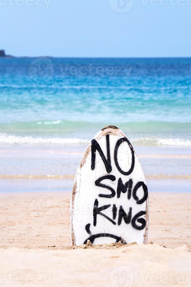 kein raucherwarnschild auf weißem surfbrett am strand im sommer, konzept des meeresumweltschutzdesigns, kopierraum, lebensstil. foto