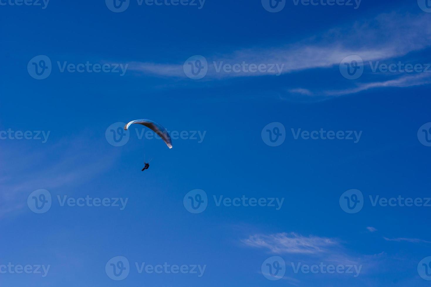 Mann auf einem Fallschirm, der in den klaren Himmel fliegt foto