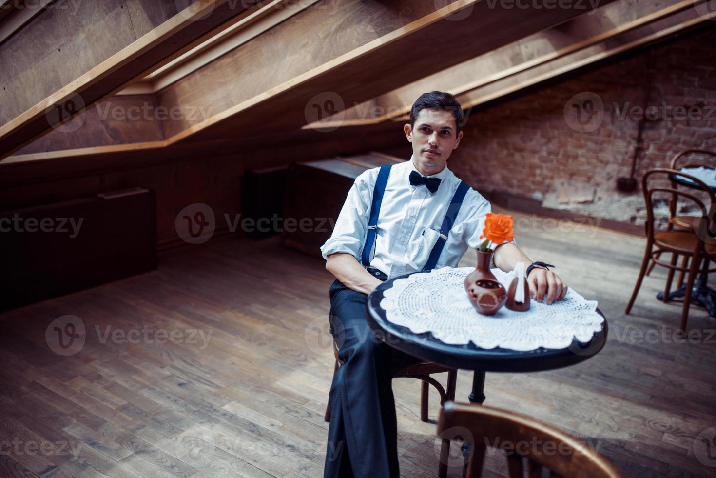 Eleganter junger Mann in Hosenträgern und Brille im Café foto