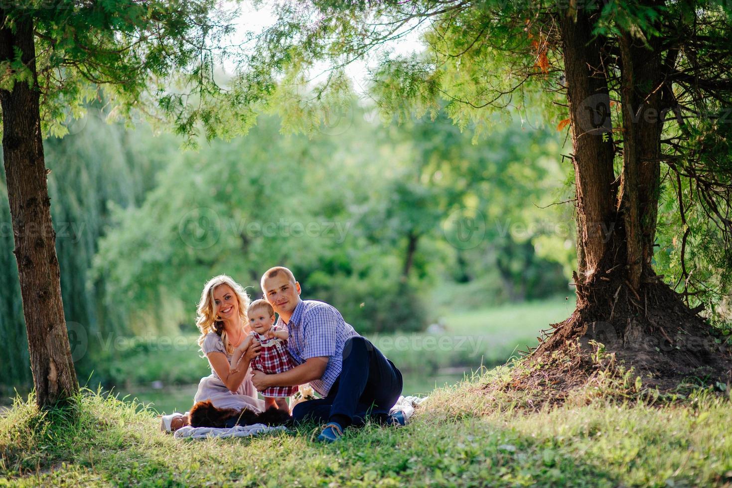 Glückliche Familie geht im grünen Sommerpark spazieren foto