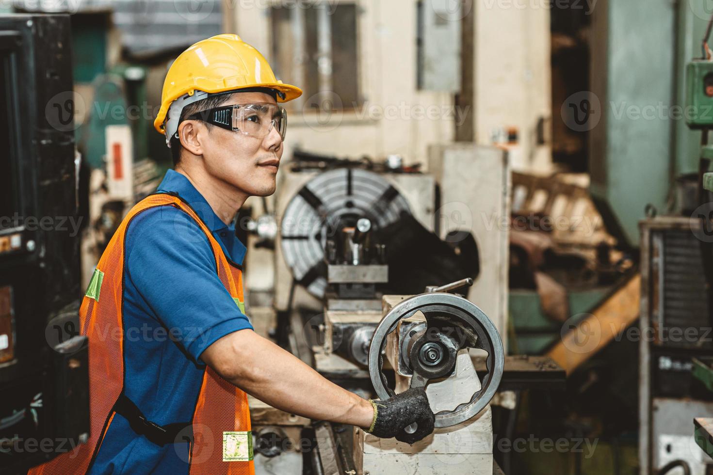 asiatischer arbeiter, der stolz auf die schwerindustrie ist und im produktionsprozess arbeitet, mit einem glücklichen lächeln in der fabrik. foto