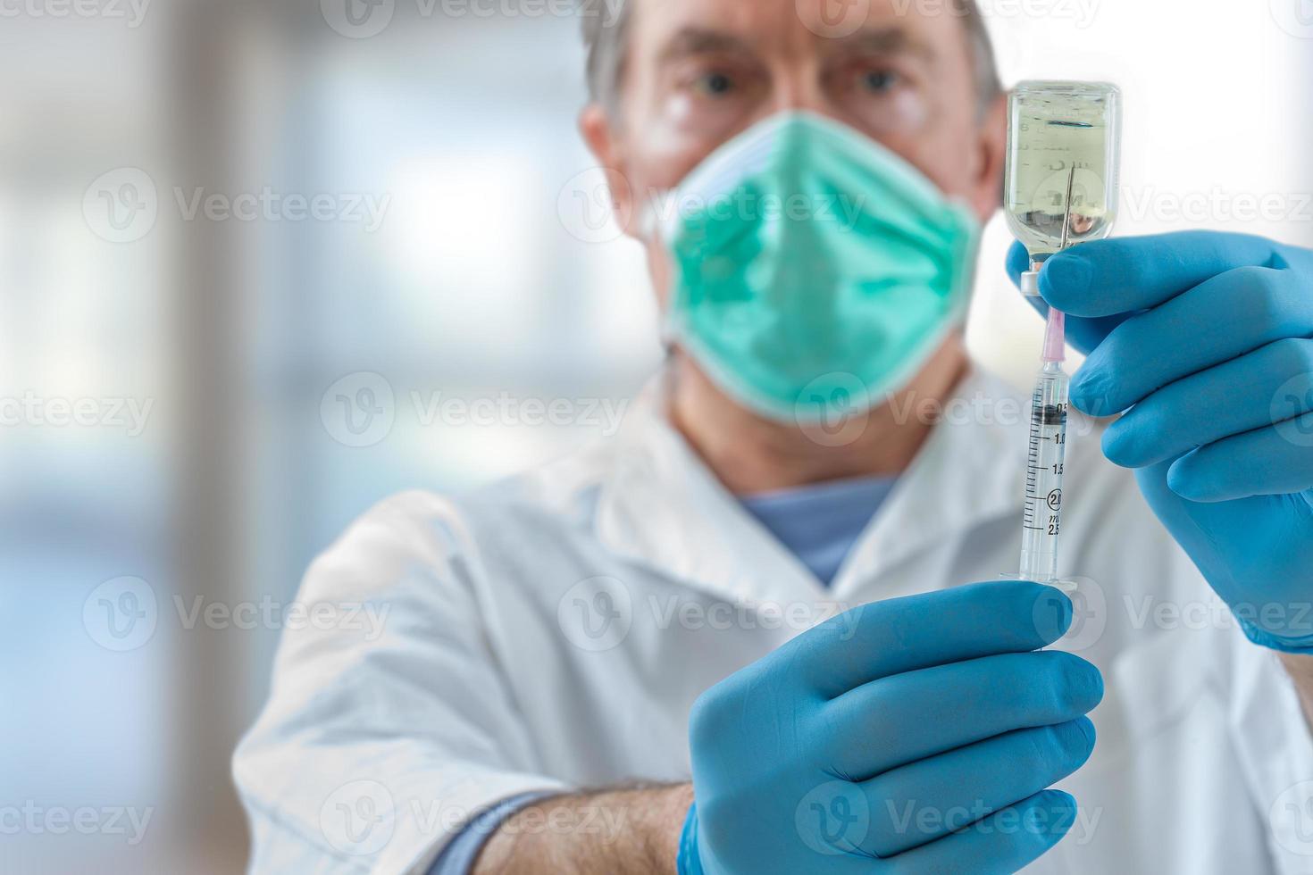 Der Arzt füllt eine Spritze mit Impfstoff auf verschwommenem Hintergrund. foto