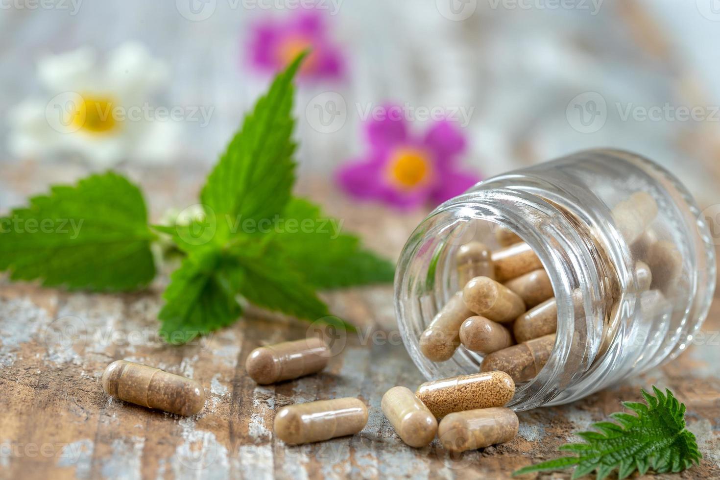 Flasche Pillen Nahrungsergänzungsmittel gesunde Medizin Medikamente Gesundheitsbehandlung Zusatzstoffe Apotheke mit frischen Heilpflanzen und Blumen im Hintergrund foto