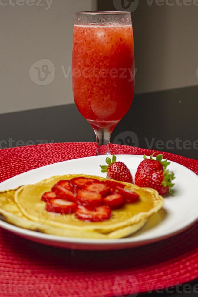 Erdbeeren und Pfannkuchen mit Sirup auf dem weißen Teller foto